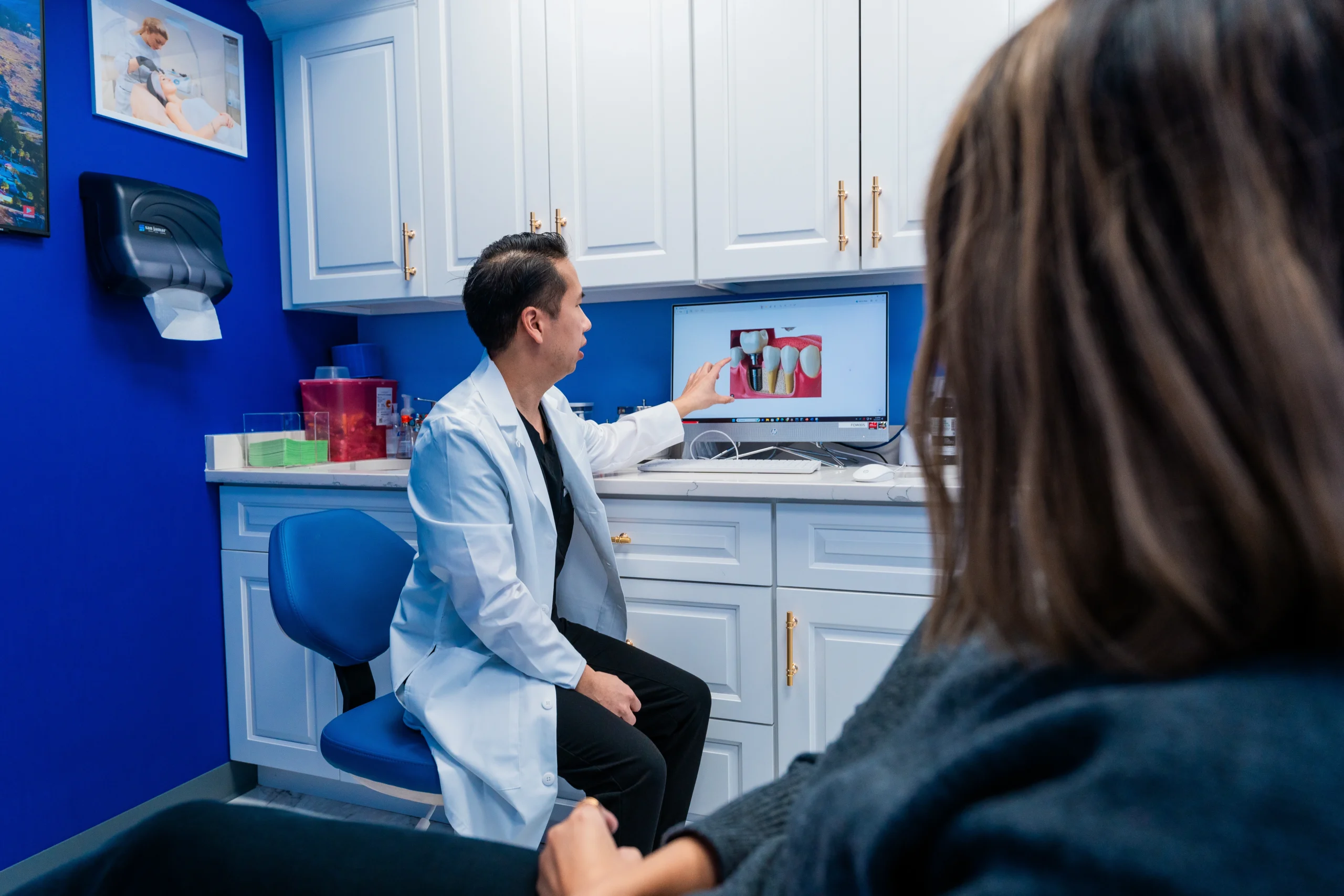 Dr. Christopher Nguyen, chatting with a patients and pointing at the computer screen